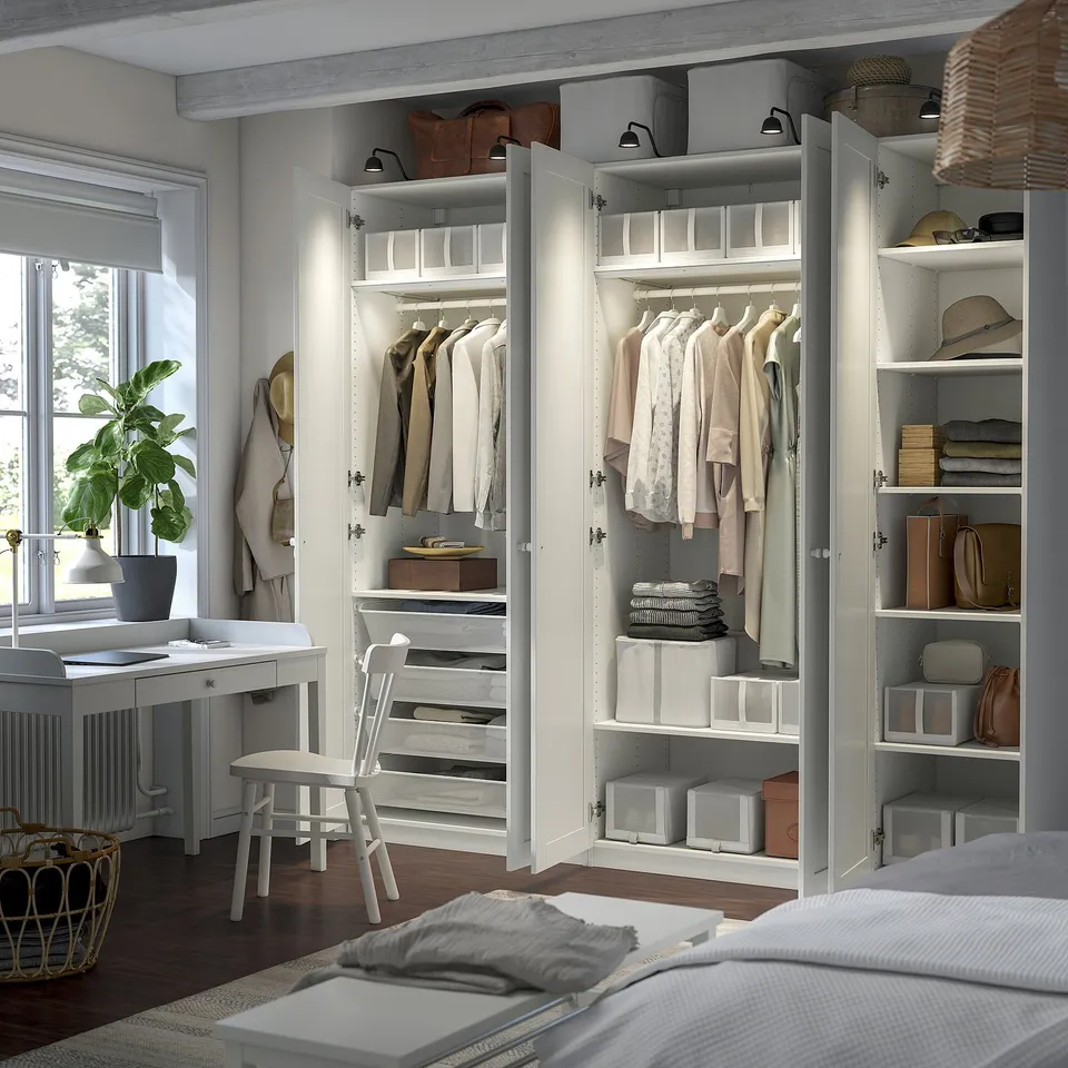 Modern PAX wardrobe with open doors, showing folded clothes and hanging garments.