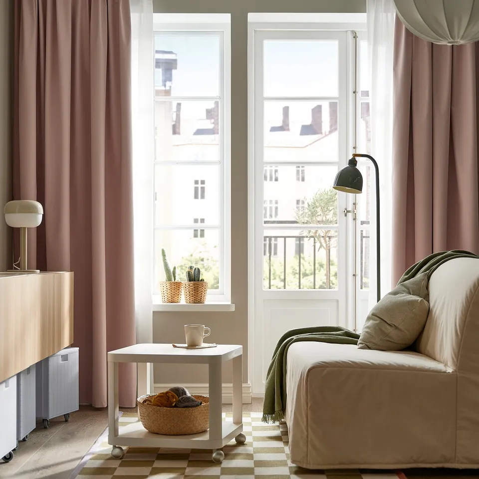 Peach pink BENGTA curtains block light, complementing neutral room decor with a cosy, inviting atmosphere.