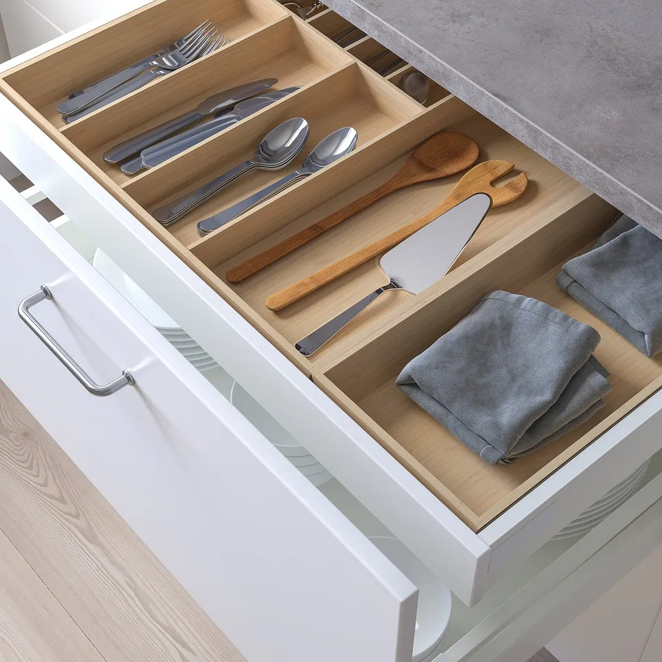 Wooden drawer organiser with dividers holding cutlery and utensils.