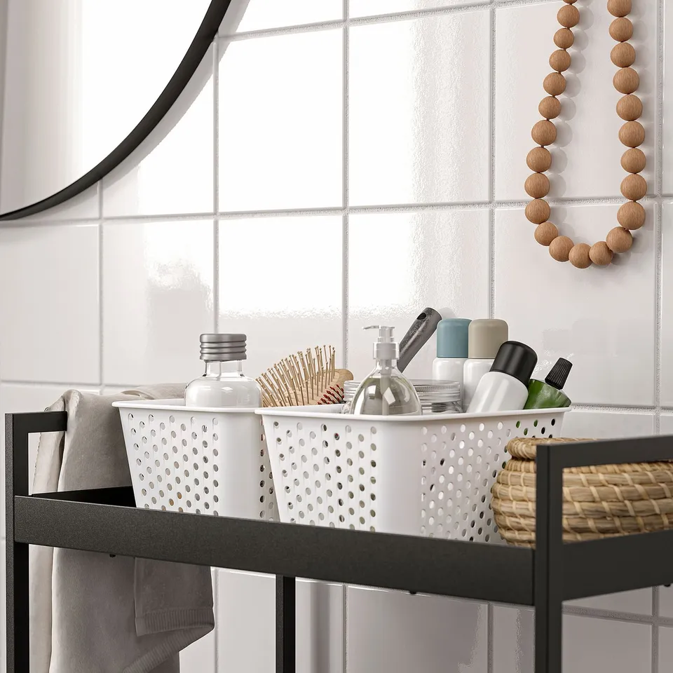 Bathroom shelf with white baskets storing toiletries and grooming items.