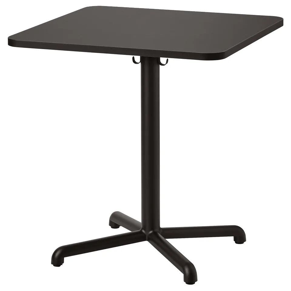A black square cafe table, STENSELE, with a sleek design. It has a sturdy steel base and a smooth particleboard top, ideal for casual seating.