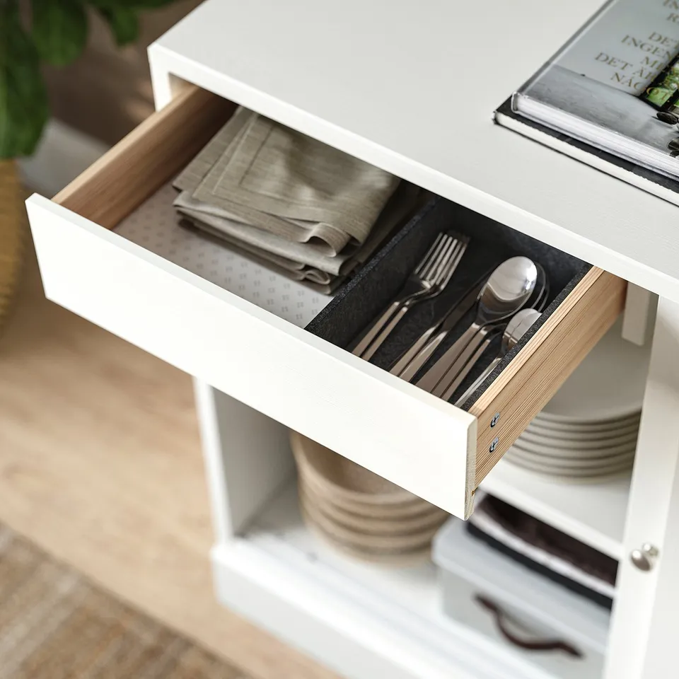Open white HAVSTA drawer reveals neatly folded napkins and organised cutlery, showcasing practical storage design.