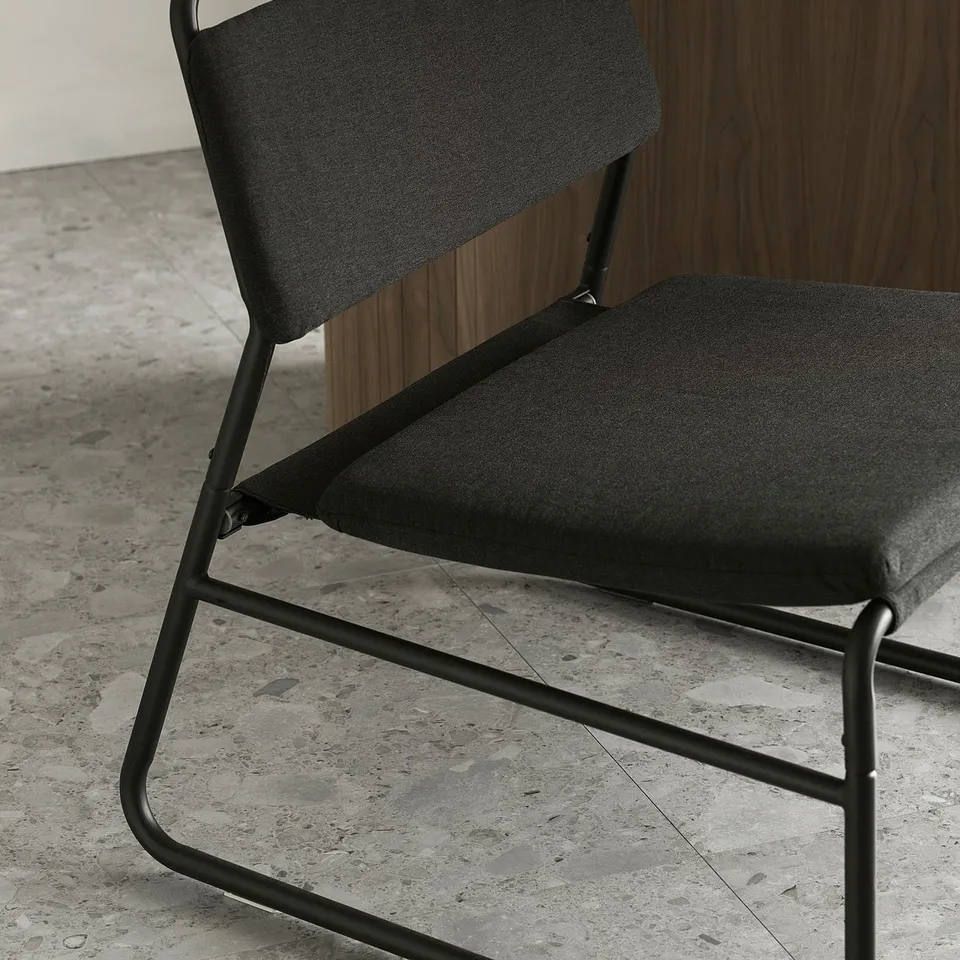 Modern black metal chair with dark grey fabric, sleek design, minimalist style.
