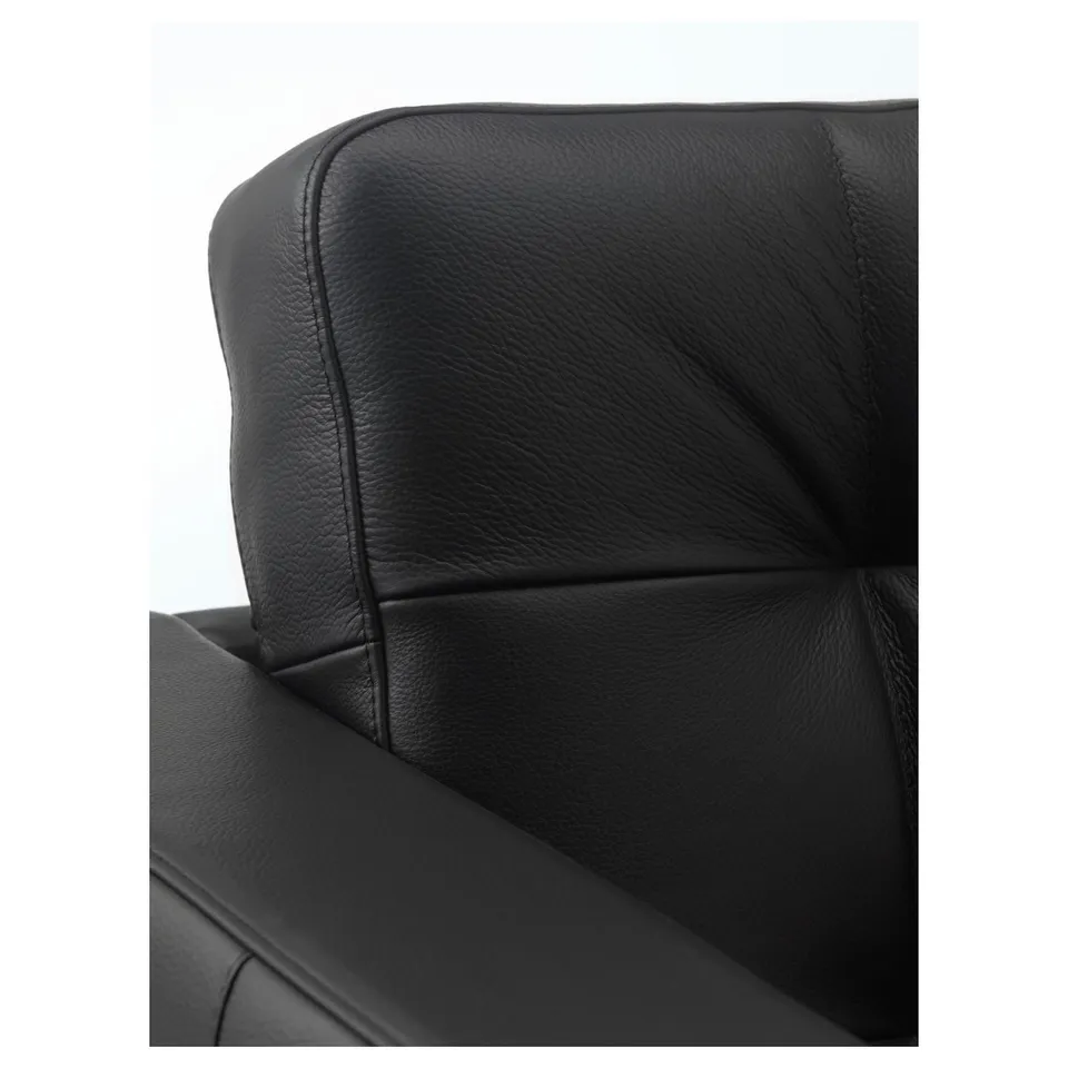 Black leather chair close-up: soft, textured grain, neat stitching, padded seat and back, suggesting comfort and durability.