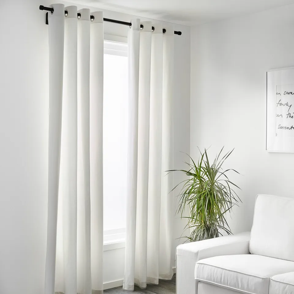 White curtains block light, providing privacy in minimalist room with plant and chair.