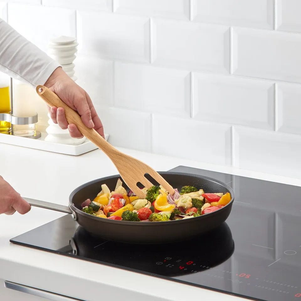 Cooking colourful vegetables in a non-stick pan on an induction stove.