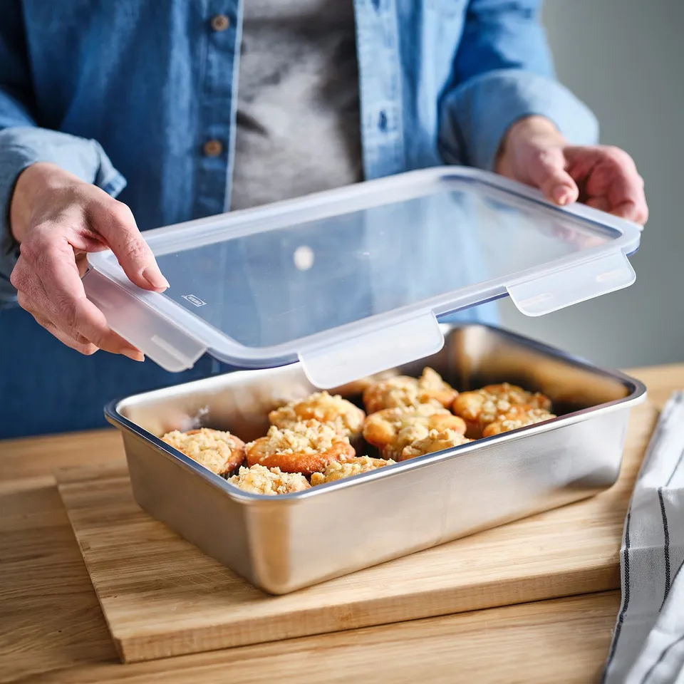 Person placing lid on food container with baked goods.