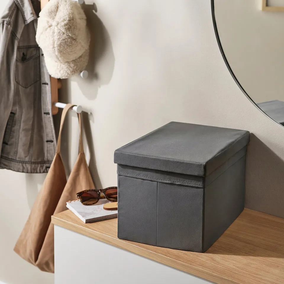 Grey storage box with lid sits on wooden shelf near coat hooks, demonstrating its space-saving organisation.