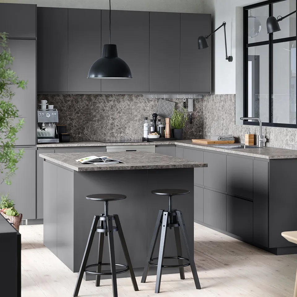 Modern grey kitchen with dark grey METOD cabinets, marble countertop, black pendant light, adjustable black bar stools, and sleek appliances.