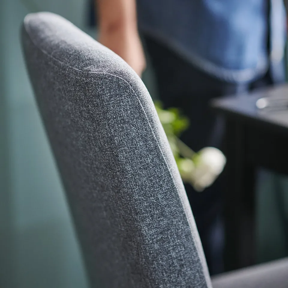 Dark grey upholstered BERGMUND office chair with wooden legs. Close-up of textured fabric.