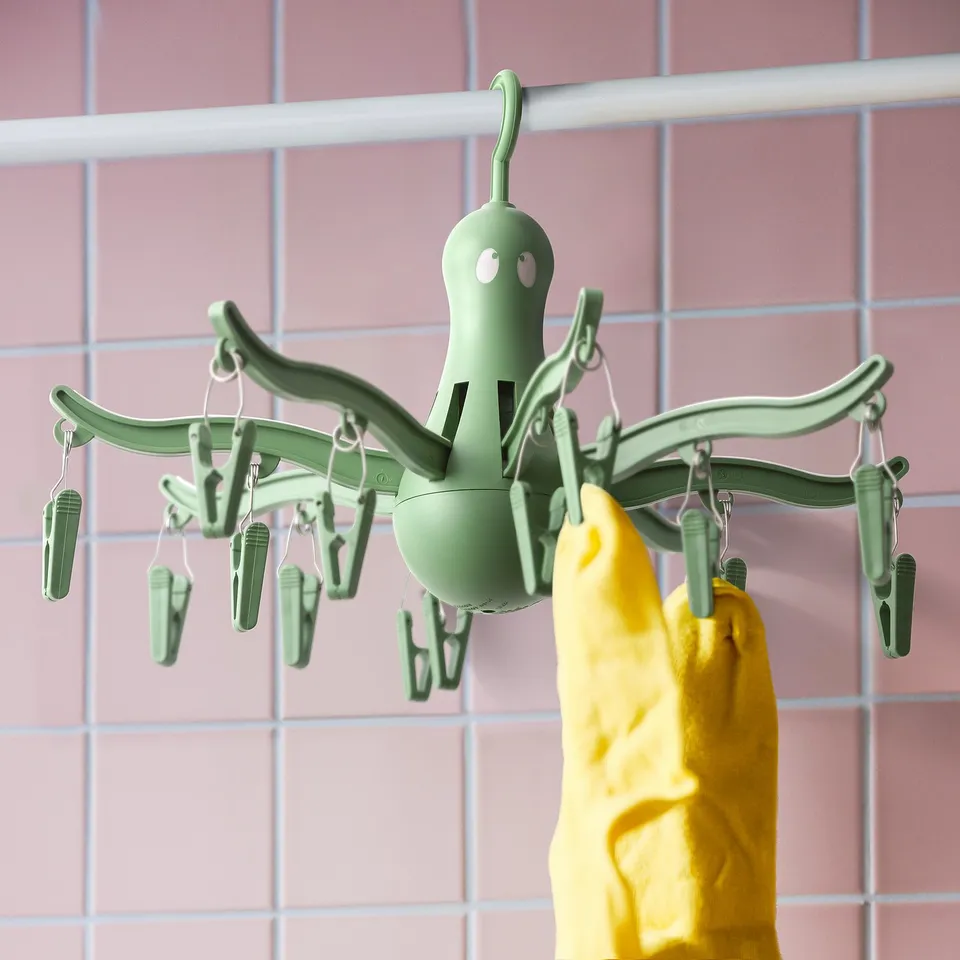 Green hanging dryer with 16 pegs, holding yellow socks, ideal for small items.