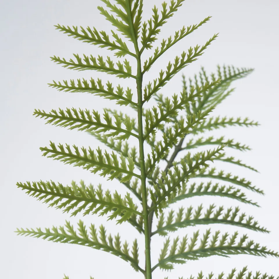 Close-up of high-quality artificial greenery, vivid green, lifelike leaves attached to adjustable steel-wired stem.