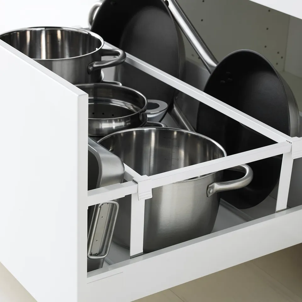 Open kitchen drawer displaying organised pots and pans on a white cabinet.