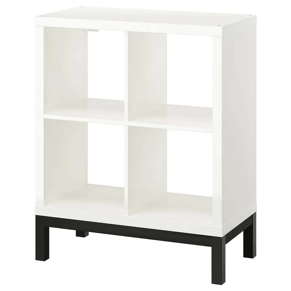 A white KALLAX shelving unit with a black underframe. It has an open, airy design with multiple compartments.