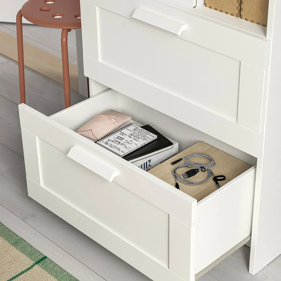 Open white drawer with books, cables, and cloth; part of a multi-piece furniture set.