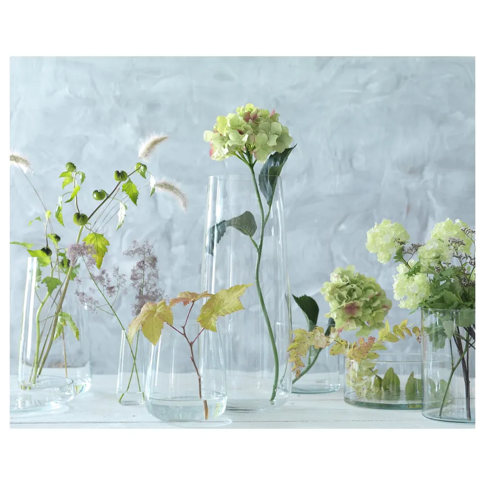 Colourful flowers in clear glass vases on light surface. Simple, elegant design.