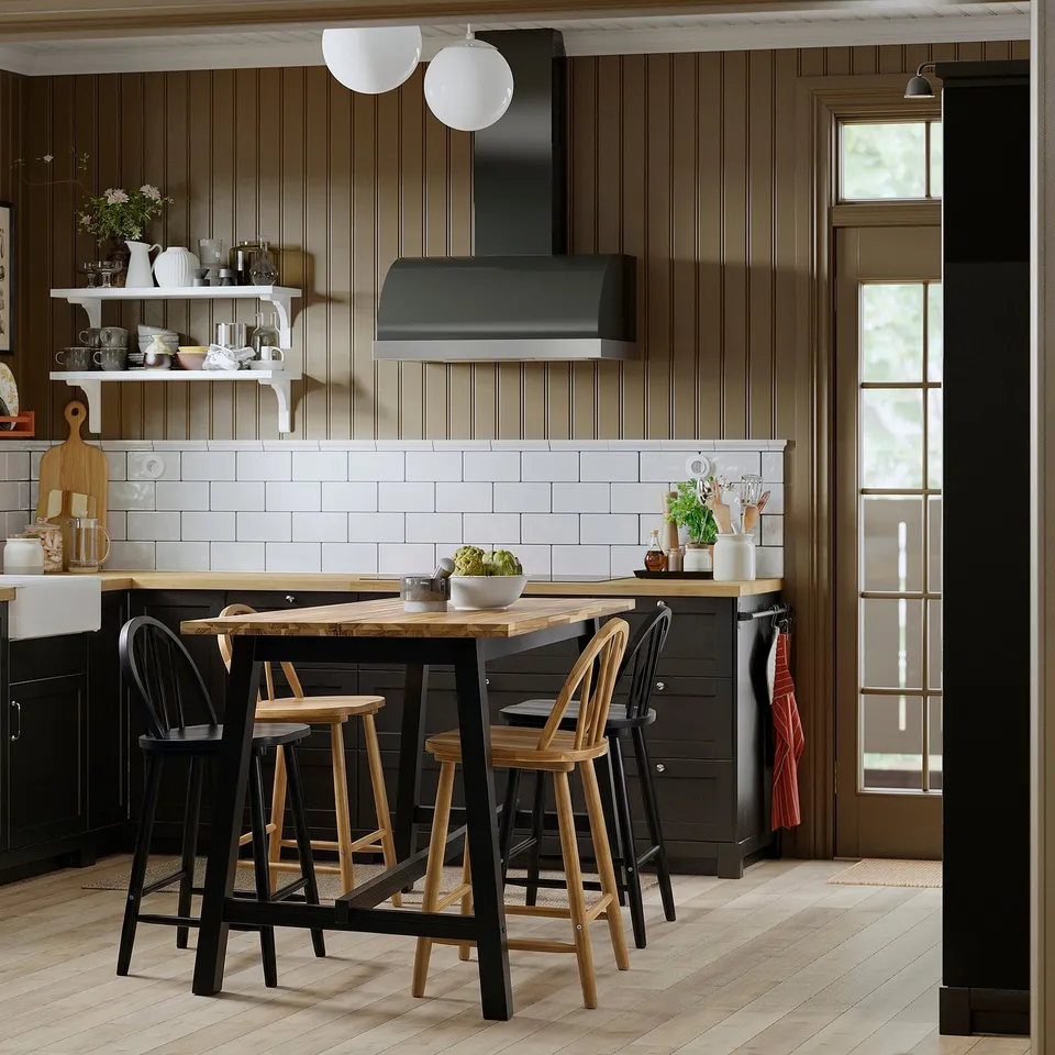 Modern kitchen with black and light wood elements; black SKOGSTA stools at centre island, complementing sleek design.