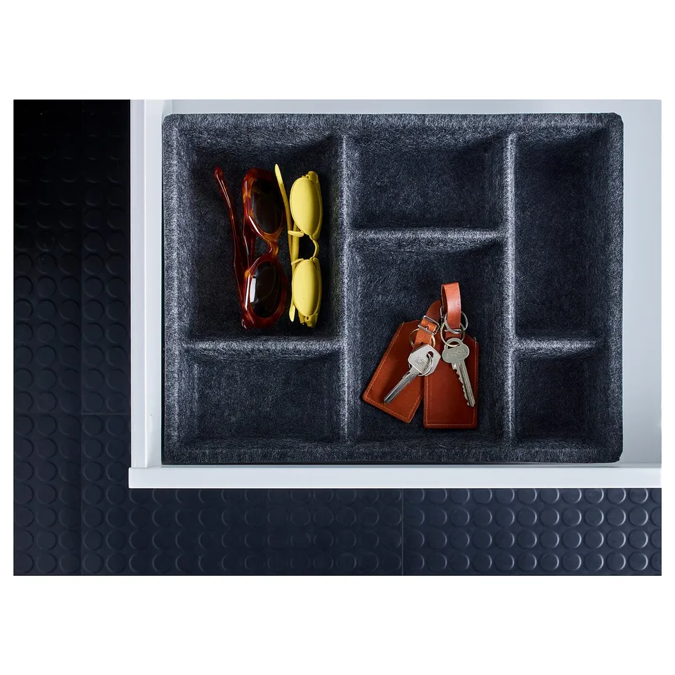 Black organiser tray with compartments, holding red and yellow sunglasses, and a keychain with keys. Made of polyester.