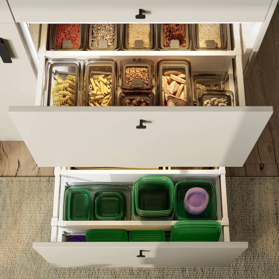 Kitchen cabinet with clear containers of dried foods. Bottom drawer holds meal prepping containers.
