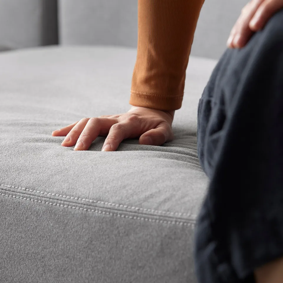 Person touching grey modular sofas cushions. The fabric is soft and smooth, ideal for comfort.