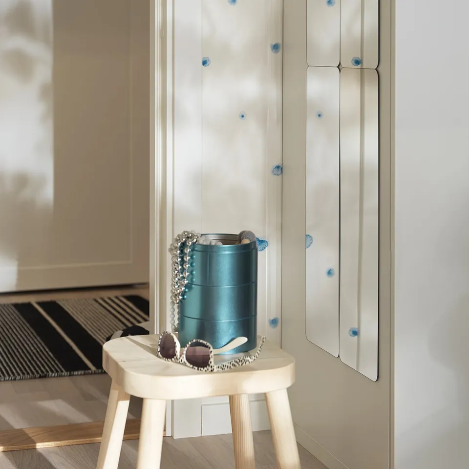 Small wooden stool with blue vase and accessories in front of a wardrobe door with a white self-adhesive mirror.