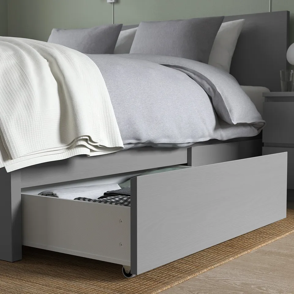 MALM bed with pull-out storage drawer and high headboard, dressed in white and grey linens.