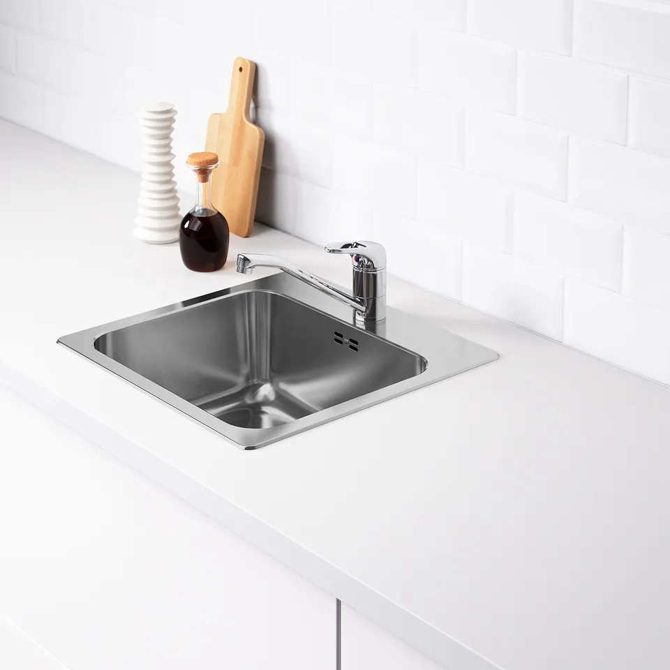 Stainless sink with modern tap, water-trap, noise-reducing material, white tiled wall.