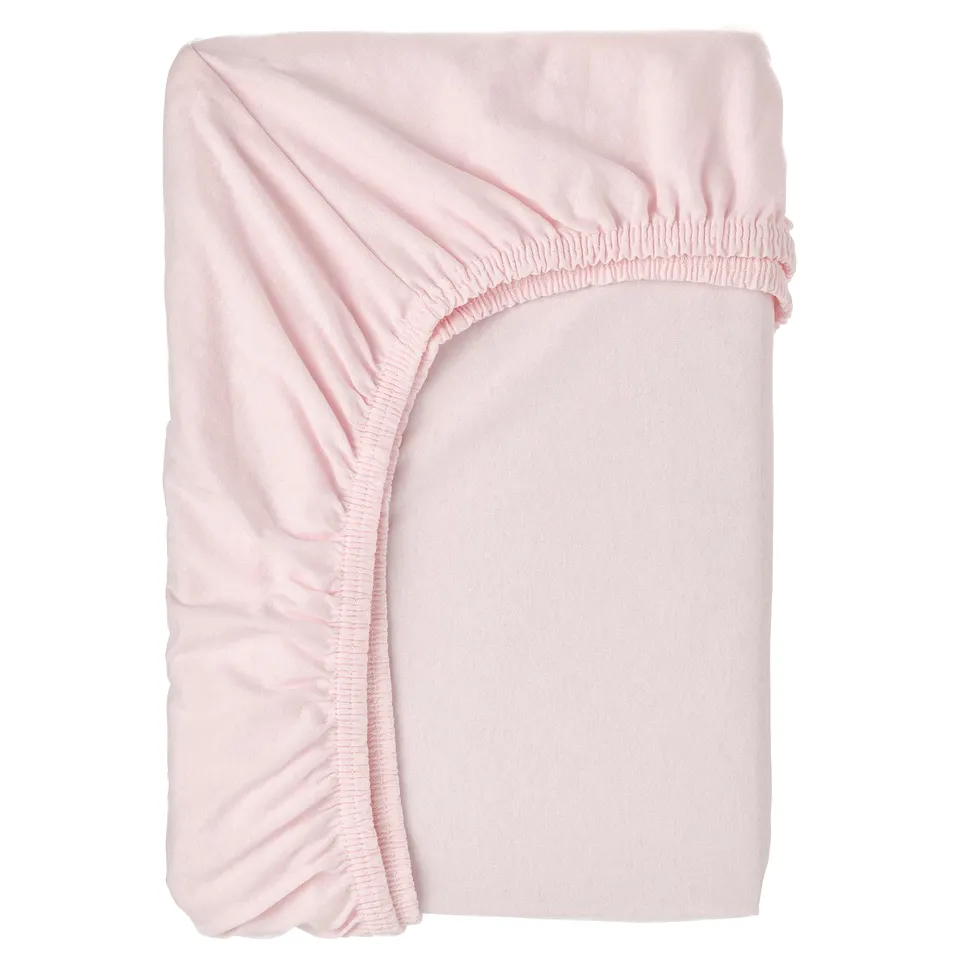 Light pink, rectangular bed sheet with ruffled edges folded neatly, made of 100% cotton.