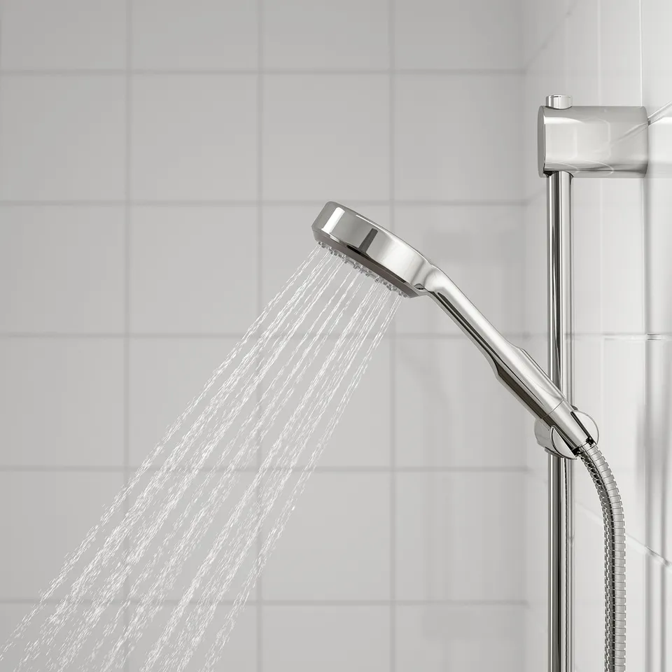 Modern chrome showerhead in action, mounted on a sturdy rail with water spraying downward.