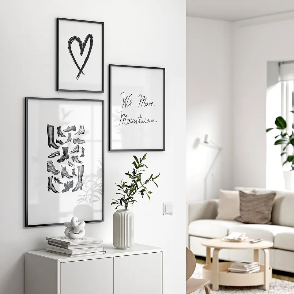 Modern living room with LOMVIKEN black framed art prints, white decor, and a cosy sofa.