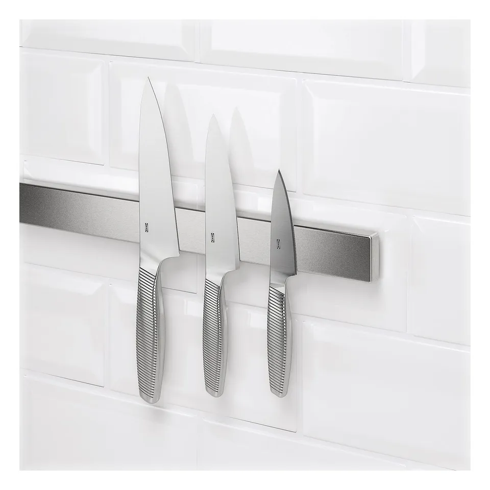 Magnet knife rack on tiled wall holding three knives. Knives securely attach and detach easily.