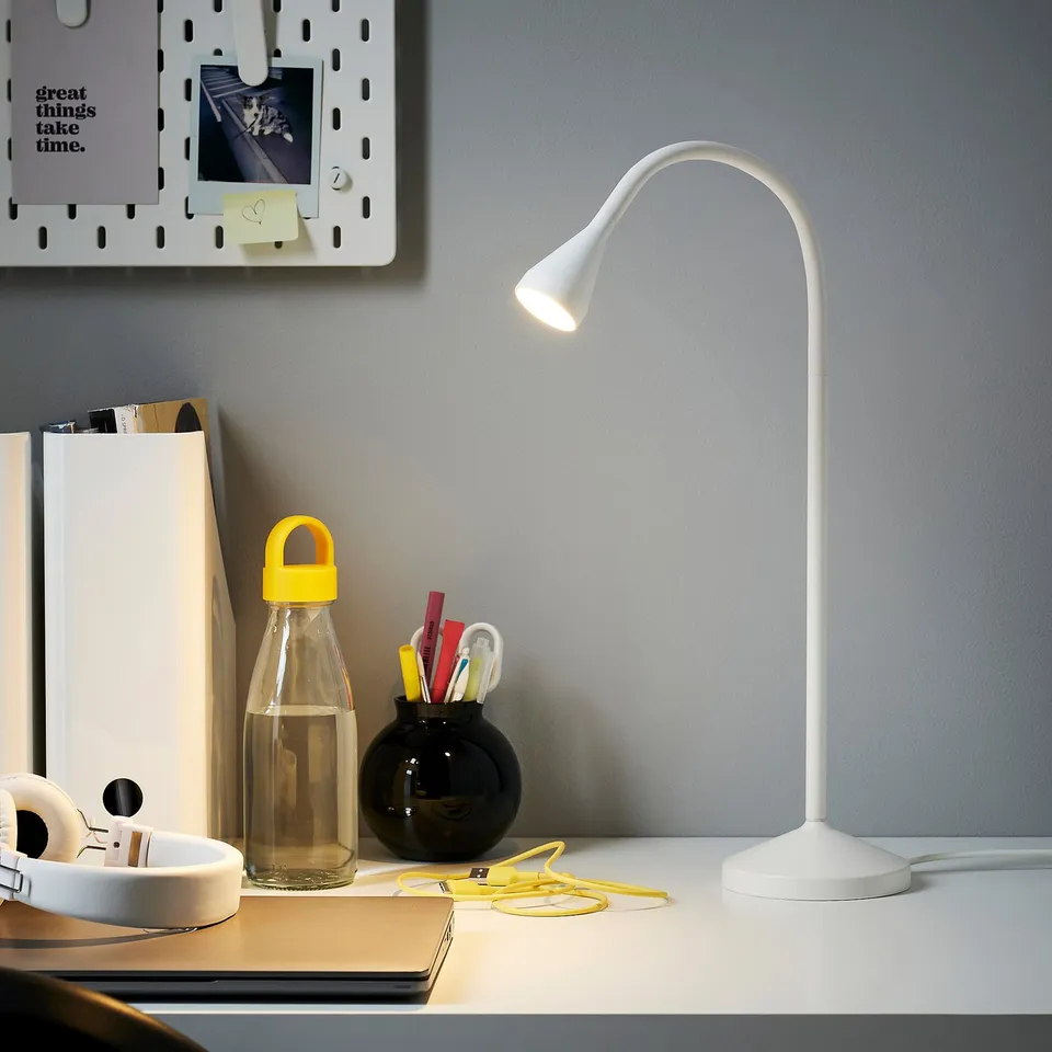 Modern workspace with ikea NÄVLINGE lamp, water bottle, pen holder, and headphones.