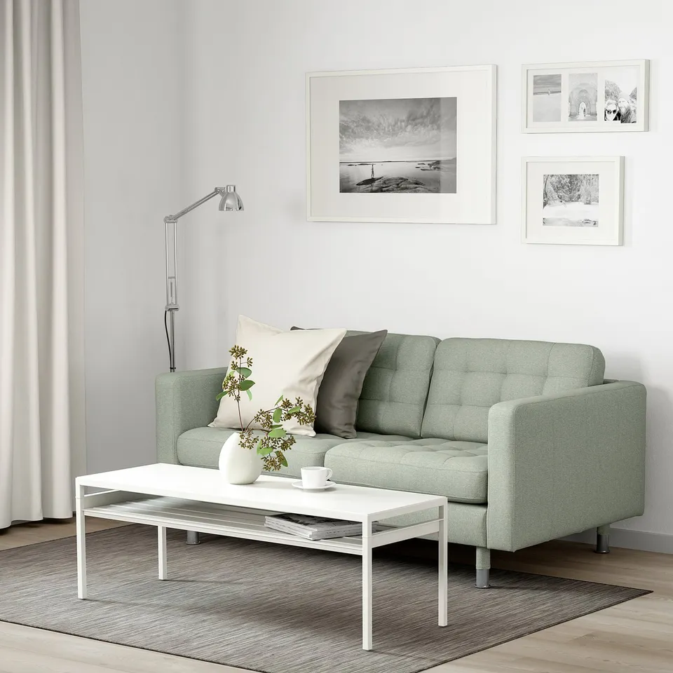 Minimalist living room: green LANDSKRONA sofa, white coffee table, black & white decor.