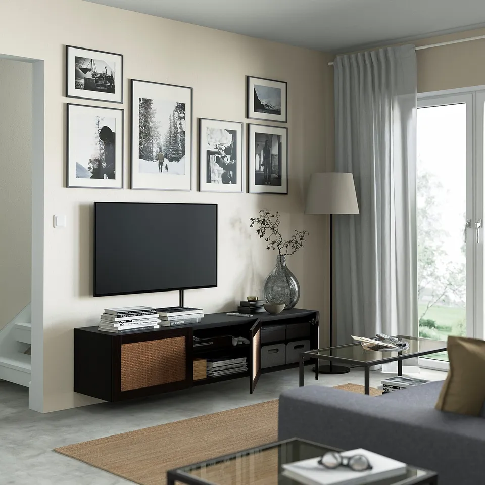 Modern living room with wall-mounted tv stand, featuring a flat-screen tv, storage shelves with books, and decorative vase.