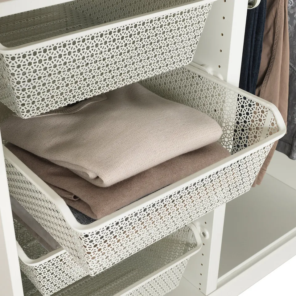 White wardrobe with mesh baskets storing folded beige clothes.