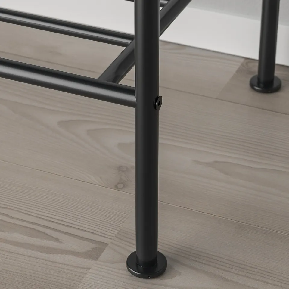 Black metal clothes rack leg with adjustable foot on wooden floor.
