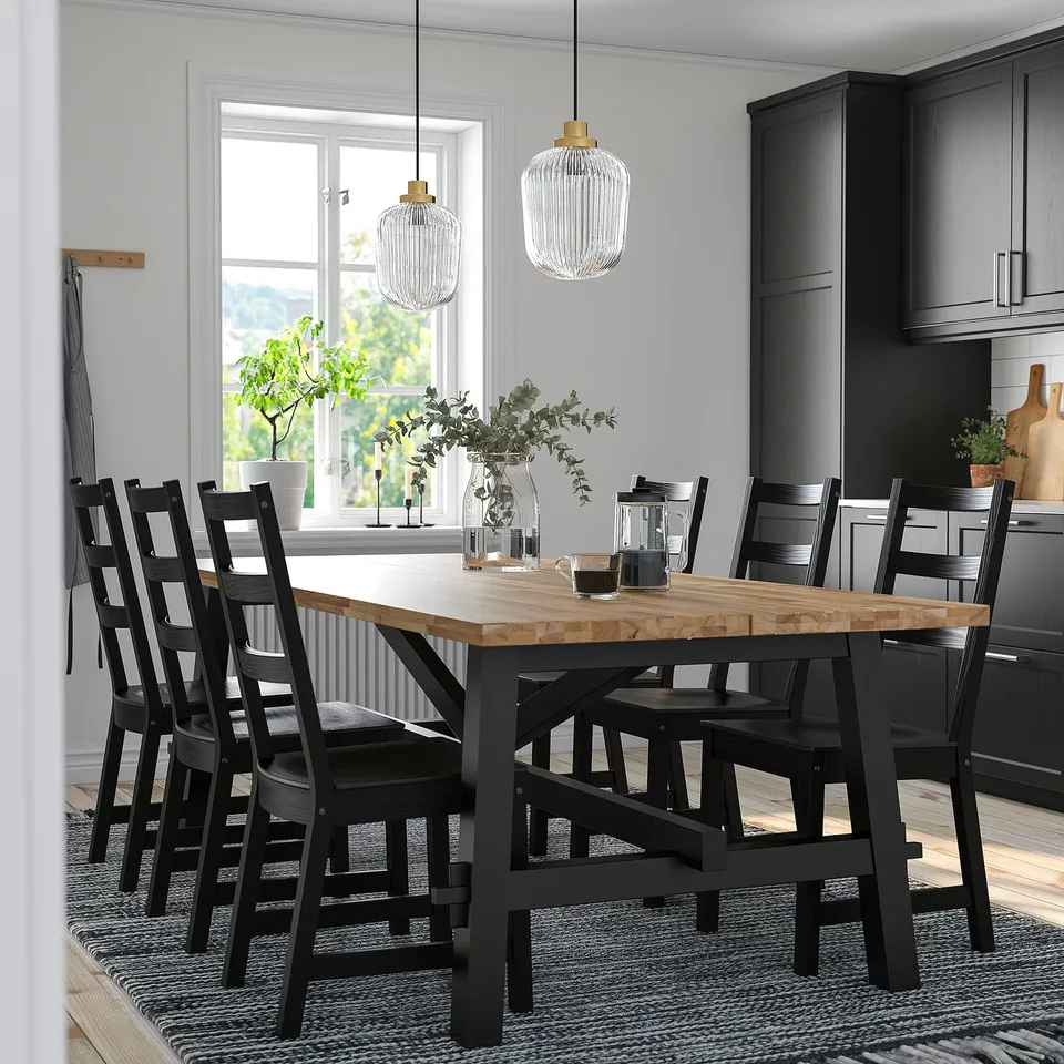 SKOGSTA dining set with wooden table, black chairs, and pendant lamps.