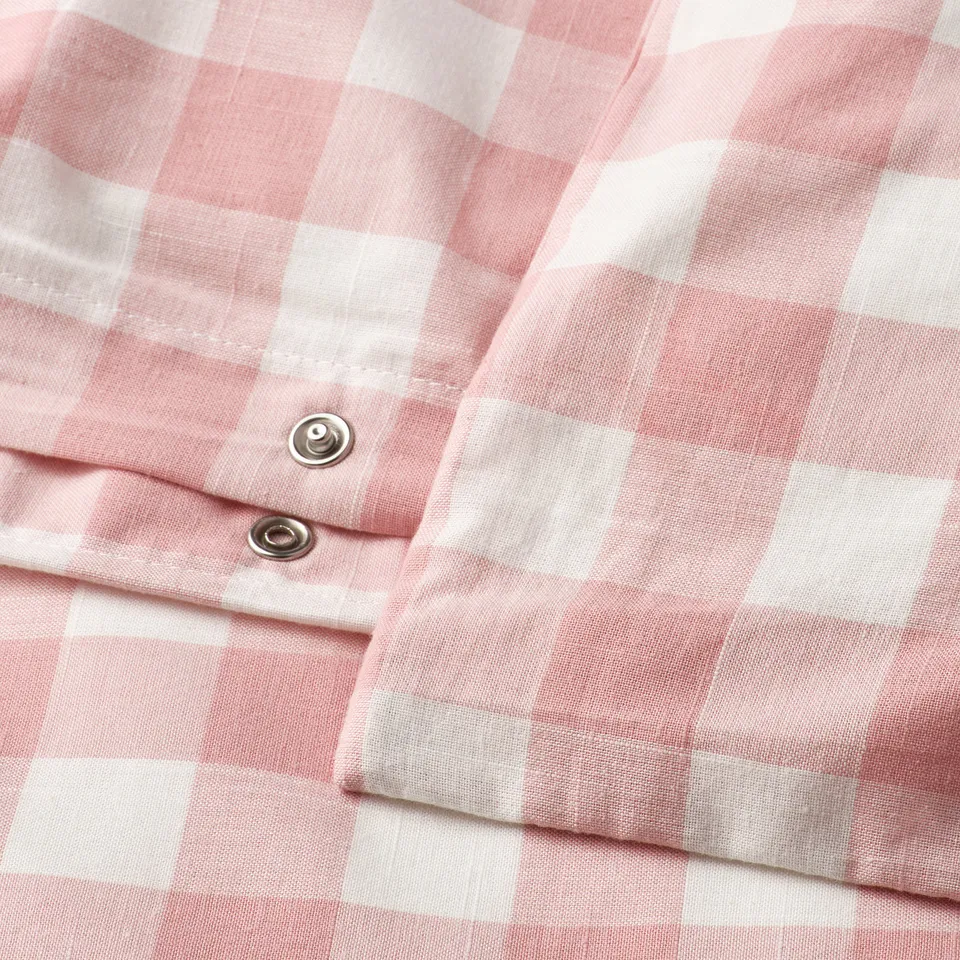 Close-up of light pink and white gingham duvet cover with metal button closure.