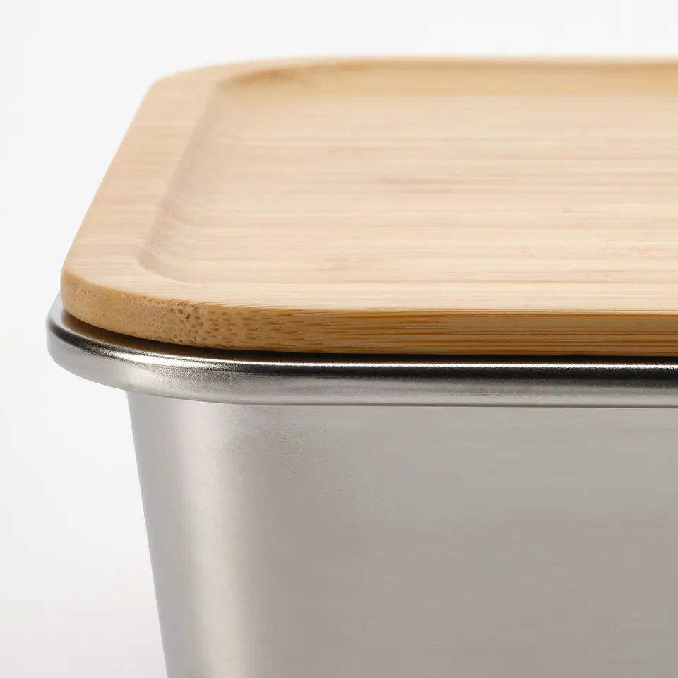 Wooden lid sits on metal container. Clean, modern design.