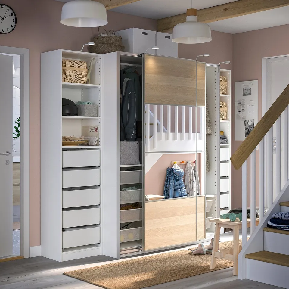 Modern white wardrobe with sliding doors, drawers, & storage. Wooden staircase, stylish home interior.