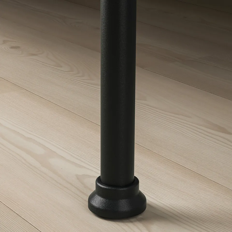 Black metal bed leg with textured finish on light wooden floor, showcasing sturdy design and quality.