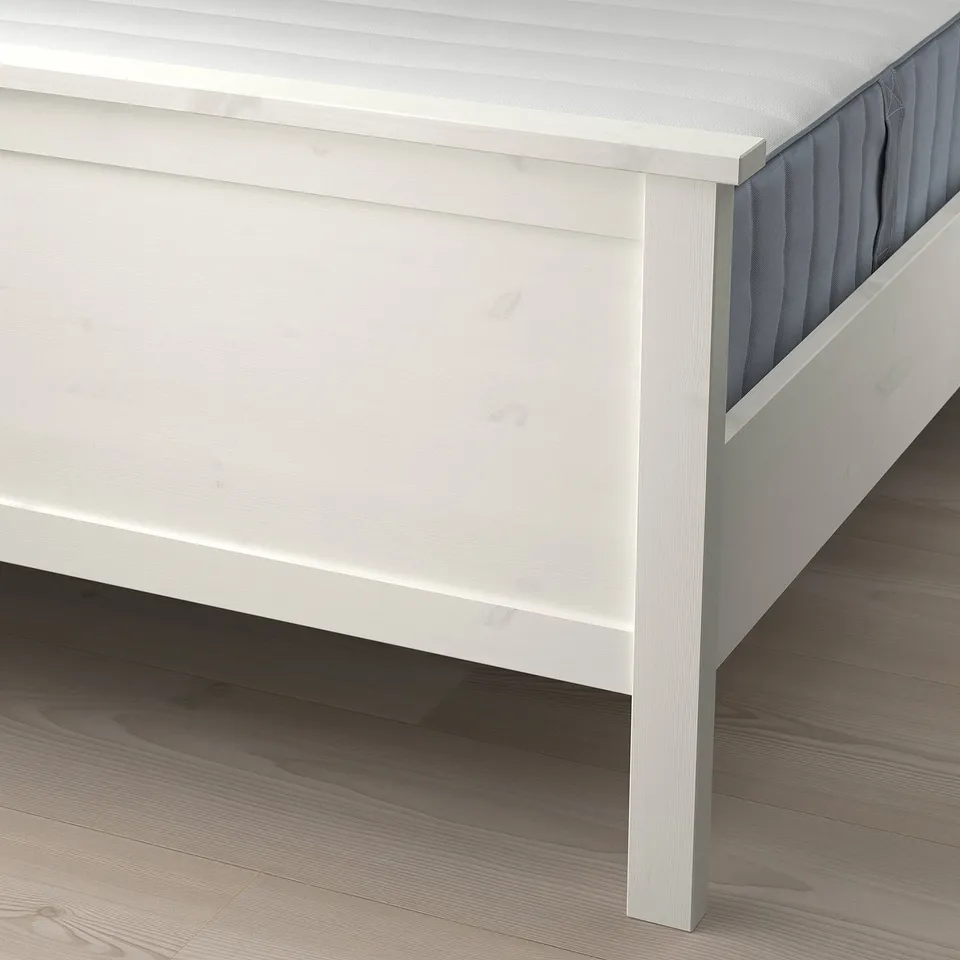 White bed frame with headboard and footboard, showing adjustable slats and sturdy design.