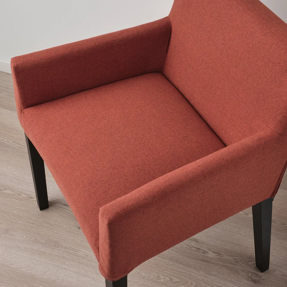 Modern dining chair with cushioned seat and backrest in rust-colored fabric supported by sturdy black legs.