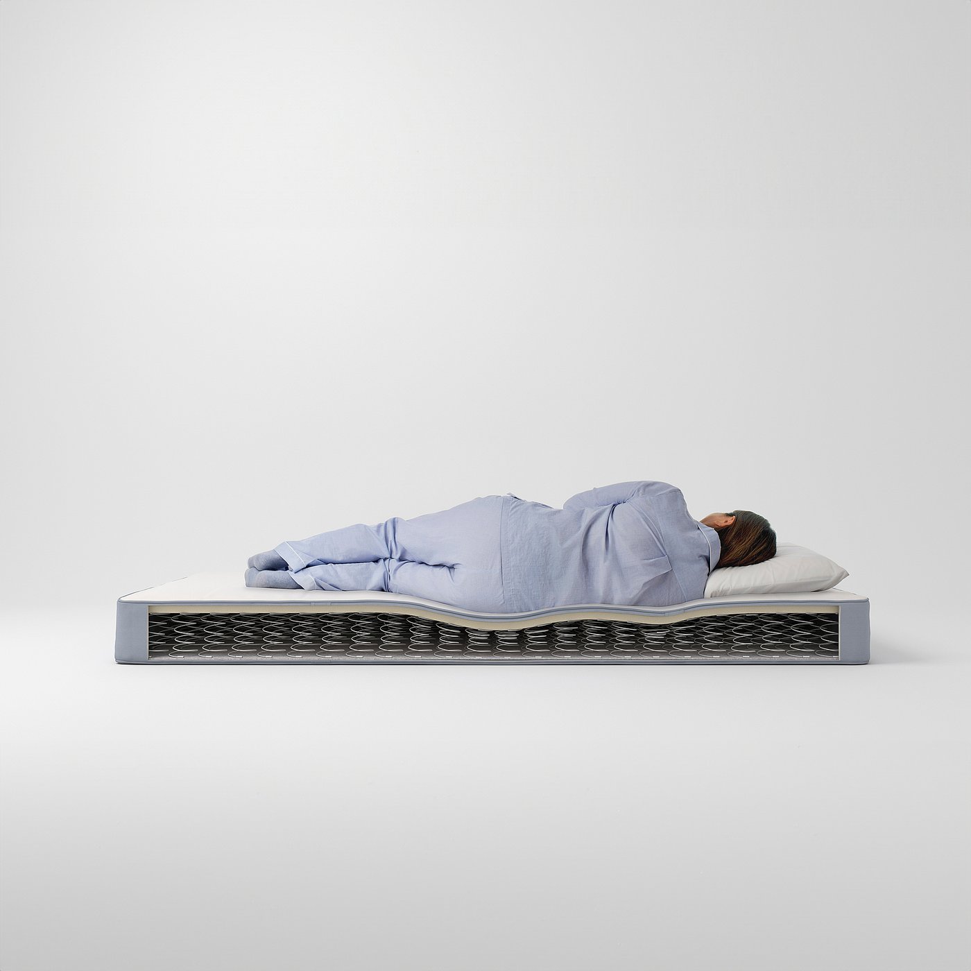 Person sleeping on blue VESTMARKA mattress with bonnell springs and foam layer.