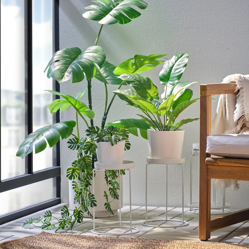 Modern living room with LÅNGNÄBB plant stand. Holds two green plants, waist-height, under a window.