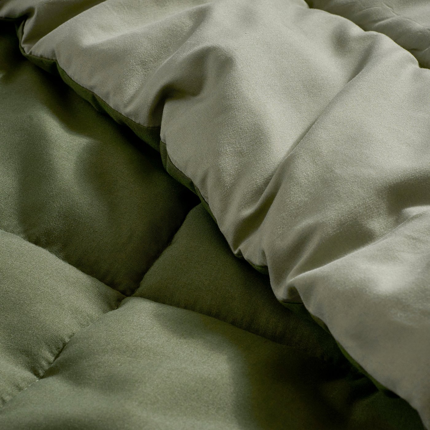 Crisp, pale green bedding with soft, neatly packed folds in a serene bedroom setting.