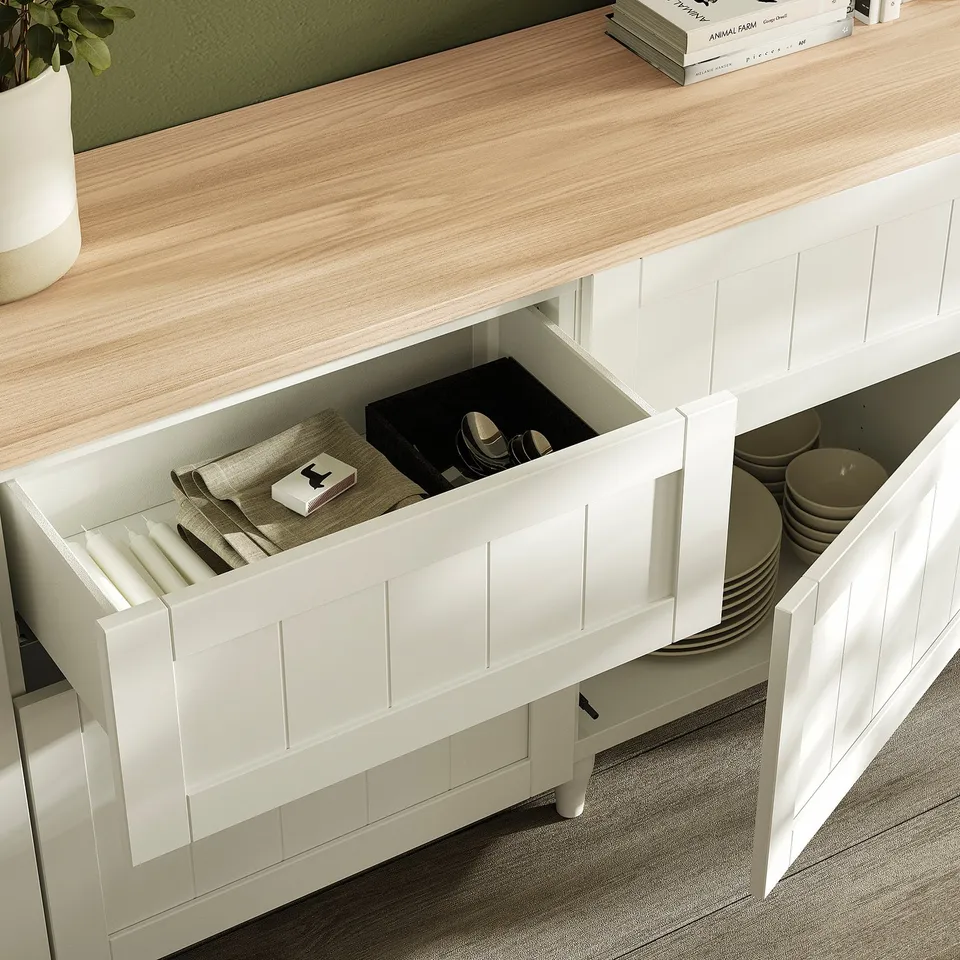Kitchen cabinet with opened drawer showing organised utensils and dishes.