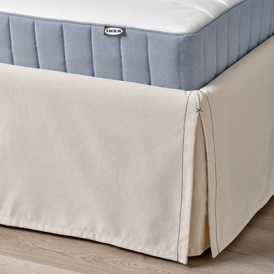 IKEA bed with soft, beige cover; removable for washing. Lightweight, sturdy, with padded headboard.