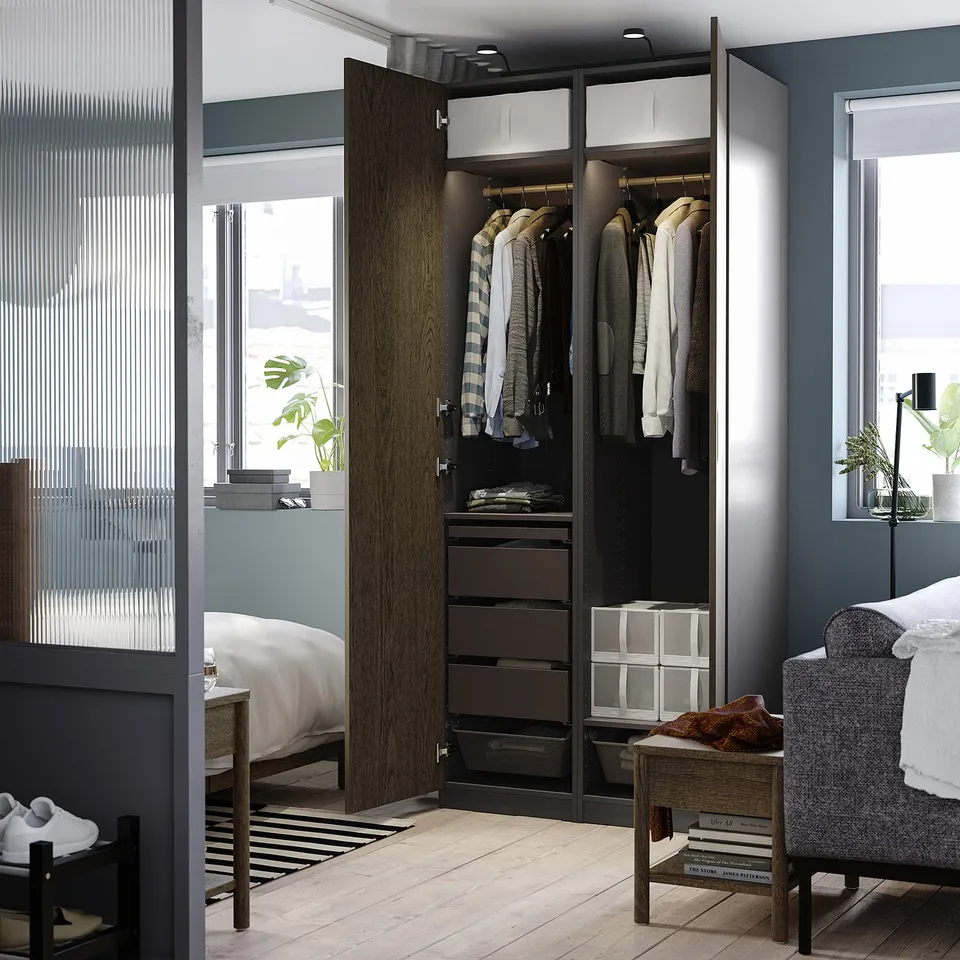 Bedroom with open PAX wardrobe displaying clothes, drawers, and trainers on the floor.
