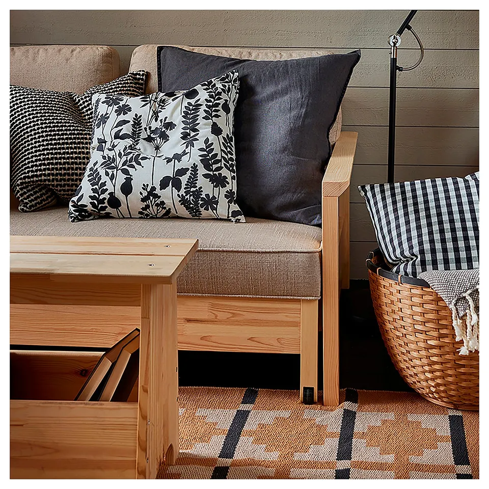 Randomization of colourful cushions on wooden furniture; a woven basket with textiles is beside it.